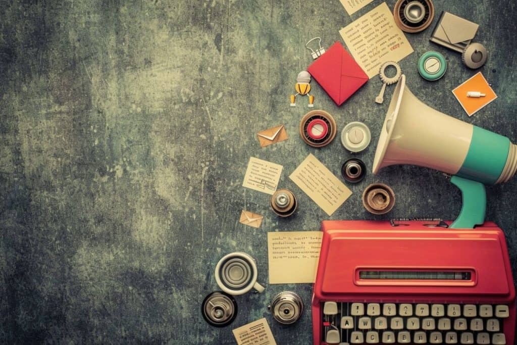 An overhead lay flat shot of a typewriter, megaphone, and other items.